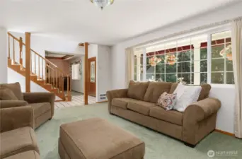 Light and bright living room with large windows with views of the the lush lawn and trees
