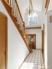 Light-filled entry with centerpiece crystal chandelier and an huge decorative wood shelf underneath window for seasonal decorating, plants, etc. Also, additional storage space under the stairs.