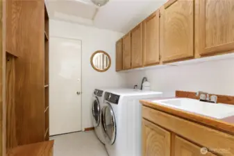 Laundry room with deep sink, lots of storage in overhead cabinets and washer/dryer/upright freezer stay