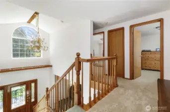 Top of staircase looking into large office with built-ins on right, and another bedroom on left