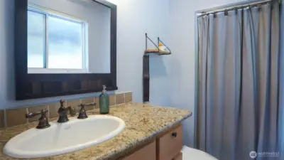 The 3/4 primary bathroom features chic granite counters, durable tile flooring, and a sleek tile shower surround, offering a stylish, modern retreat for daily comfort.