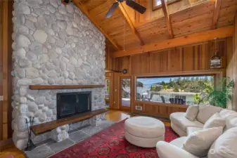 Airy living room with picture window, fireplace and vaulted ceilings.