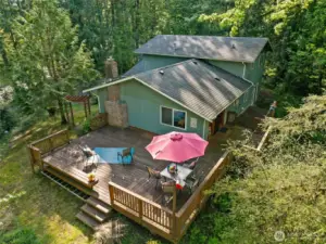 An aerial view of the South East side of the home shows the expansive decking and privacy trees.