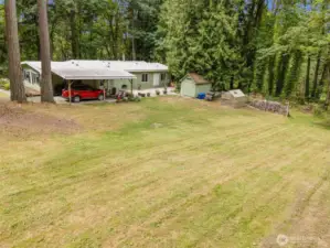 Here you can also see one of the outbuildings, as well as the greenhouse and some firewood for you to burn in a Summer firepit or on those cold Winter nights.