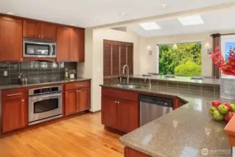 Beautifully appointed kitchen features expansive slab granite counters with complementary hardwood cabinets and backsplash.
