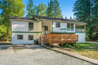 Front approach highlighting generous driveway space, gravel parking area, and welcoming covered entry