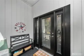 Welcoming covered porch with decorative glass double doors, providing sheltered access and a charming first impression.