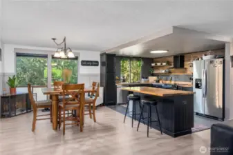 Open-concept dining space with large windows for natural light, seamlessly connected to the kitchen with breakfast bar seating.