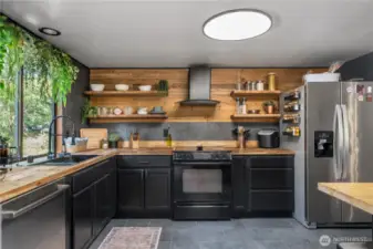 Spacious kitchen with stainless steel appliances, open shelving, and modern black-and-wood finishes.