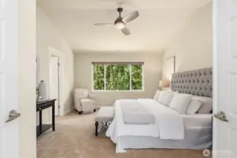 Spacious primary bedroom with vaulted ceilings and large window bringing in ample natural light.