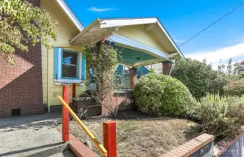 The exterior features a carriage porch, wooden shutters, a terraced front landscape & a level backyard.