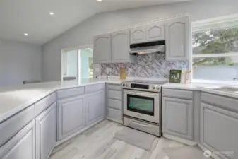 Light-filled, updated kitchen with modern finishes, generous counter space, ample cabinets, stainless steel appliances, and a a cheerful backsplash.