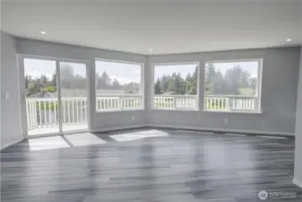 Upstairs bonus area is flooded with natural light through a wall of oversized windows and a sliding glass door that opens to a private balcony, offering treetop views and endless possibilities — perfect for a second living area, home office, playroom, or entertainment space, all with sleek dark hardwood flooring and recessed lighting.