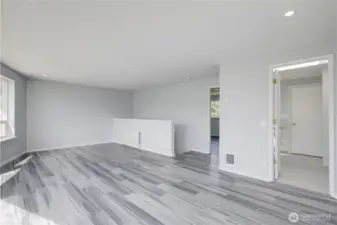 Upstairs bonus area is flooded with natural light through a wall of oversized windows and a sliding glass door that opens to a private balcony, offering treetop views and endless possibilities — perfect for a second living area, home office, playroom, or entertainment space, all with sleek dark hardwood flooring and recessed lighting.