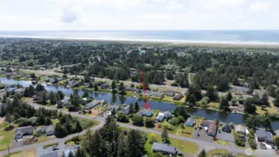 This stunning aerial view showcases the property's unbeatable location — tucked along a peaceful canal with direct water access, all just a short stroll from the Pacific Ocean beach, surrounded by towering evergreens and the natural beauty of the Washington coast.