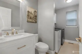 Downstairs half bathroom/laundry room. New vanity, mirror, lighting, toilet, and porcelain floor tile.