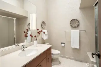 The en suite bathroom for bedroom #3 is filled with natural light from a skylight and features a spacious vanity, soaking tub, and walk-in shower.