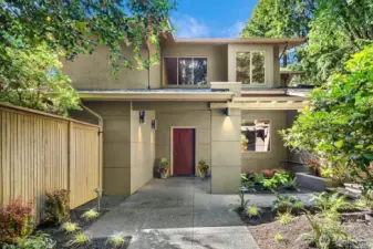 Lined with lush landscaping and shaded by mature trees, the elegant front walkway offers a warm welcome with dappled natural light.