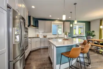 Kitchen with oversized island with eating area, stainless steel appliances, gas range, ample cabinetry