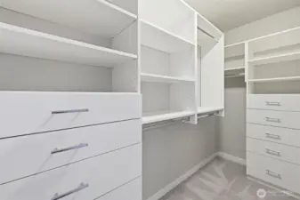 The primary bedroom walk-in closet features built-in drawers, shelves and places to hang clothes.