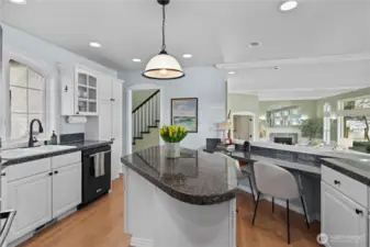 Light-filled kitchen with granite countertops, ample cabinetry, and a central island, seamlessly connected to the living spaces and showcasing beautiful water views beyond.