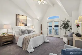 Wake up to breathtaking waterfront views in this light-filled primary suite with vaulted ceilings and balcony access.