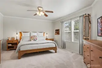 Primary bedroom suite has serene views and ceiling fan.