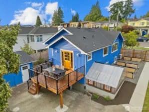 An ideal outdoor living space with a generous deck, lush lawn, greenhouse, garden beds, and room to relax or play.