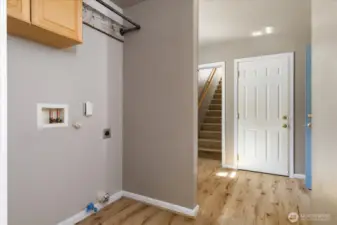 Laundry room and mud room area with stairs on left to 2nd floor family room. White door is garage, blue door is mud room entrance from wrap around porch