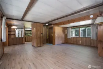 Open living space featuring exposed beam accents and durable flooring, creating a warm and functional environment. The layout offers flexibility for everyday living, entertaining, or customizing to fit your needs.