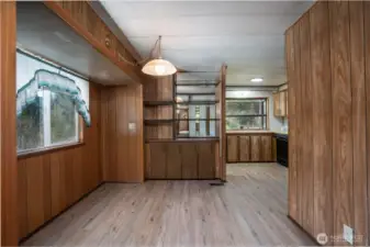 Dedicated dining area with natural light from the window and a central fixture, creating a comfortable space for everyday meals. Built-in shelving adds character and functionality while maintaining easy flow into the kitchen.