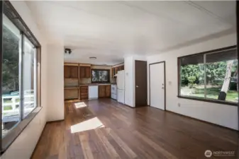 Bright and open living area with large windows that bring in natural light and views of the surrounding property. Seamless flow into the kitchen creates a functional layout