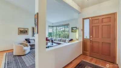 Looking back to the front door the hardwood floors gleam and the living room shows it's vaulted ceiling.