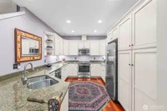 The lovely white cabinetry of the kitchen with newer appliances, granite countertops, and under-cabinet lighting.