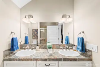 Dual vanity of the Primary en suite bathroom, and a fully tiled walk-in shower with sliding doors.