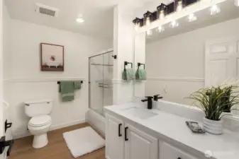 Updated family bath with new countertops, lighting and hardware. Tub with shower enclosure and sliding glass doors.