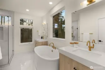 A chic spa-inspired luxurious bathroom, which includes a large glass-enclosed walk-in shower, and soaking tub.