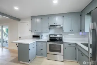 Beautifully remodeled kitchen with Quartz Countertops. Dining room off to the left of this photo with sliding glass door access to covered concrete patio. Dining bar with space for bar stools. Appliances included.