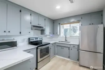 Beautifully remodeled kitchen with Quartz Countertops. Dining room off to the left of this photo with sliding glass door access to covered concrete patio. Dining bar with space for bar stools. Appliances included.