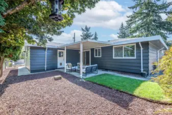 Photo from NE Side of property looking at covered patio & access to kitchen or passage door to garage.  Clear pathways to easily access all sides of the home.