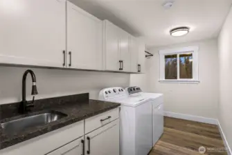 This utility room turns doing laundry into a dream! Plenty of storage space, folding space, large sink and hanging bar installed.