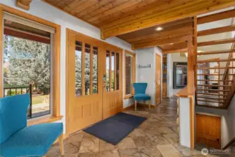 View of entryway with French doors, slate tile flooring looking towards the Primary suite with views of the stairs up to the upper level bedroom/bunk room and stairs leading down to the lower level w/ 2nd living room and kitchen and additional bedrooms.