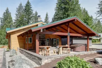 Expansive outdoor living area, A stone-clad chimney or fireplace, Custom wood plank table and bar stools, hot tub, Stamped concrete Patio and walkways.