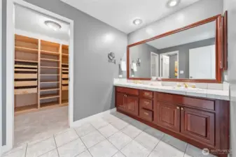 The primary bath showcases cherry wood cabinetry, dual sinks, and an oversized mirror—ideal for streamlined morning routines. A medicine cabinet offers added storage, while the ceramic tile flooring ensures easy maintenance.
