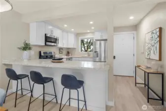 Open concept kitchen with quartz surfaces and is a perfect match to the newly installed vinyl plank flooring throughout.  All appliances transfer with property.