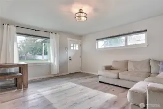 Bright living room with LVP flooring, updated lighting, and large windows for natural light.