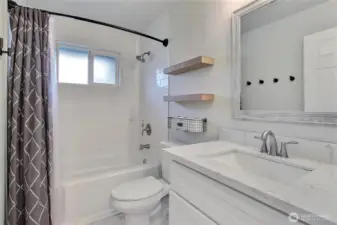 Updated full bathroom with newer tub and tile surround, modern vanity, and quartz countertop.