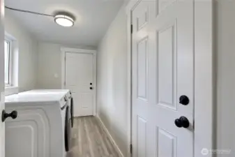 Utility room with front-load washer and dryer included and exterior door leading to the backyard.
