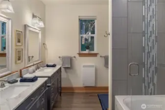 Elegant bathroom featuring dual vanities with marble counters, a spacious tiled shower, and warm natural finishes.