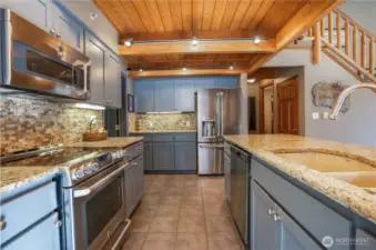 Great kitchen layout with custom cabinets, granite countertops, custom tile back splash, stainless steel appliances and tile floors! Beyond is the hall to the a full bath & utility room.